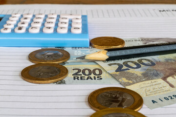 new Brazilian money bills and coins on the table with calculator. Two hundred reais.
