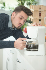 man standing at kitchen counter in the morning pouring coffee