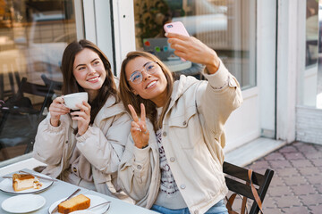Two cheerful girls friends taking selfies