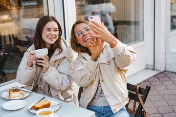 Two cheerful girls friends taking selfies