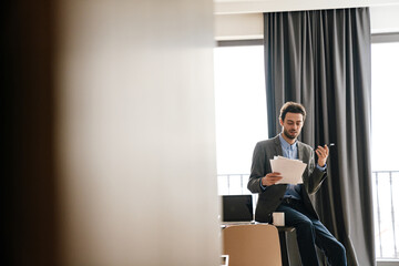 Serious businessman talking on mobile phone while examining documents