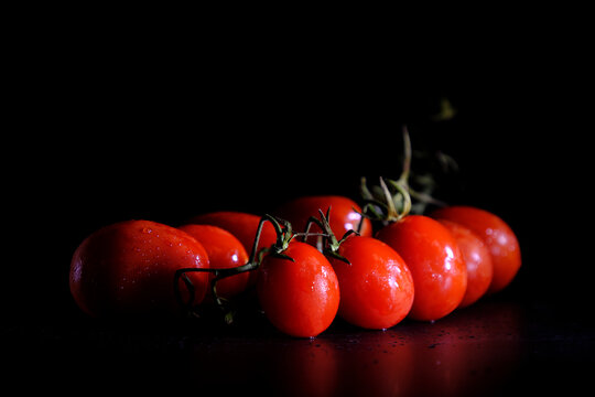 Fresh red cherry tomato bunch on a black background
