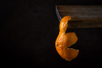 The tangerine peel hangs from the wooden surface. Citrus fruit. Mandarin zest