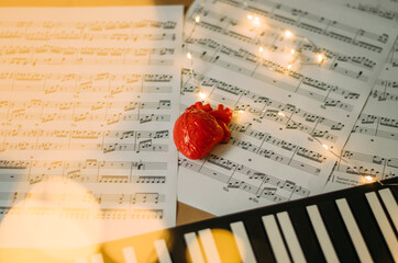 Heart on piano note sheets with bokeh Christmas lights effect 