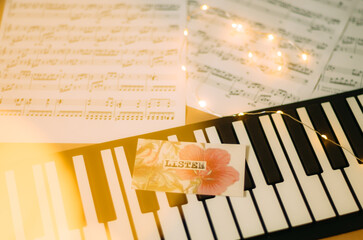 Electronic piano and note sheets with Christmas warm light and a card with the word 