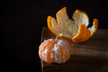 Peeled tangerine on a wooden surface. Citrus fruit. a peeled tangerine lies next to a tangerine peel.