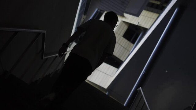 Man walking up stairs towards aesthetic building in the dark with silhouette in slow
