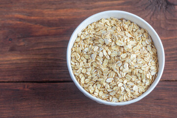 Traditional large oat flakes in a bowl on a wooden background with a copy of the space.The view from the top.