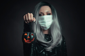 Young beautiful witch holding a pumpkin