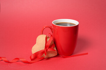 red cup with gingerbread heart and red ribbon on red background, valentine's day holiday. the mocap copyspace