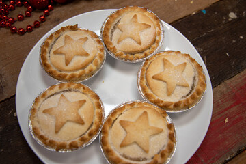 A plate of delicious Christmas mince pies on a wooden work top