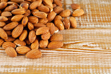 Almonds on a pink scratched board. Texture of nuts on a wooden old table. Lots of nuts in a pile. Place for text and copy space near seeds.