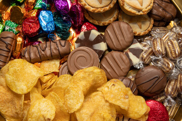 A delicious plate of a large selection of treats chips and chocolates