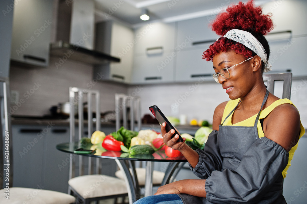 Wall mural african american woman filming her blog broadcast about healthy food at home kitchen and looking at 