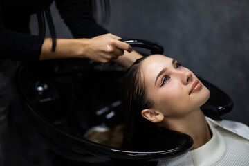 Smiling attractive woman with her eyes closed in enjoyment having a hair shampoo at the hair salon