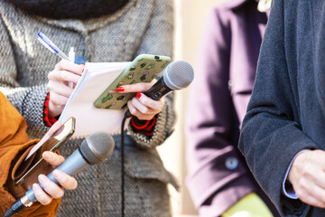 News reporter or TV journalist at press conference, holding microphone and writing notes - obrazy, fototapety, plakaty