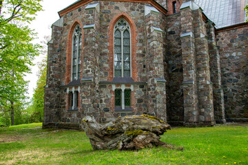 Latvia - The Cesvaine Lutheran Church, a building of colored stones, a large driftwood on a green lawn.