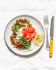 Cauliflower fritters with smoked salmon and greek yogurt sauce on a light background, top view