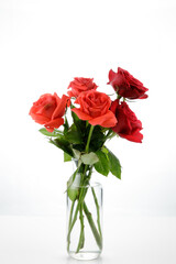 a bouquet of red and orange roses on a glass jar fill with water isolated on white background