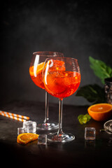 Aperol spritz cocktail in glass with fresh orange on dark background