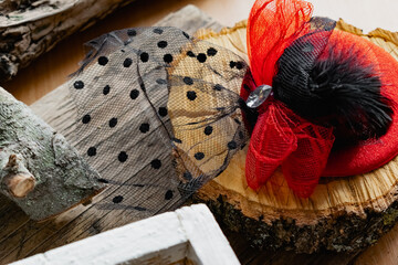 Decorative hat on a hair clip with a red bow and a black veil. Accessory for a themed party or...