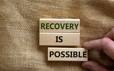 Recovery is possible symbol. Wooden blocks with words 'Recovery is possible'. Beautiful canvas background, male hand. Copy space. Business and recovery is possible concept.