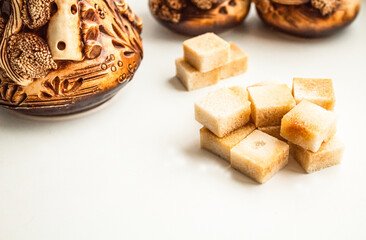 A handful of cane sugar against the backdrop of a beautiful ceramic set