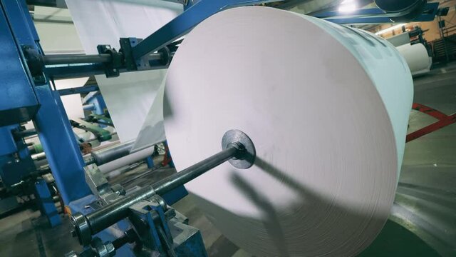 Industrial mechanism with a massive roll of paper spinning on it