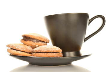 Fototapeta na wymiar Several delicious shortbread biscotti cookies on a saucer with a cup, close-up, isolated on white.