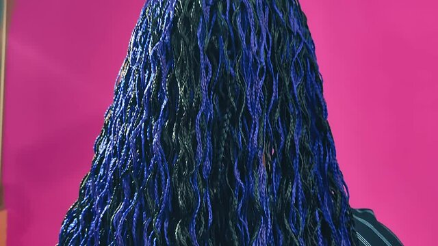 Rear view of a Jewish woman with blue Afro braids turns her face with a smile. Close-up