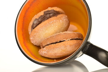 Two delicious biscotti shortbread cookies with ceramic black cup, close-up, isolated on white.