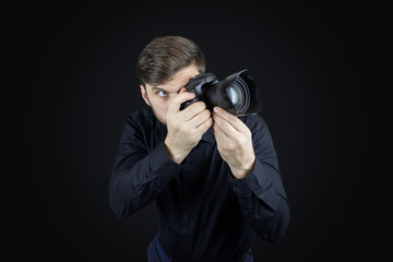 a male photographer looks through the camera's viewfinder
