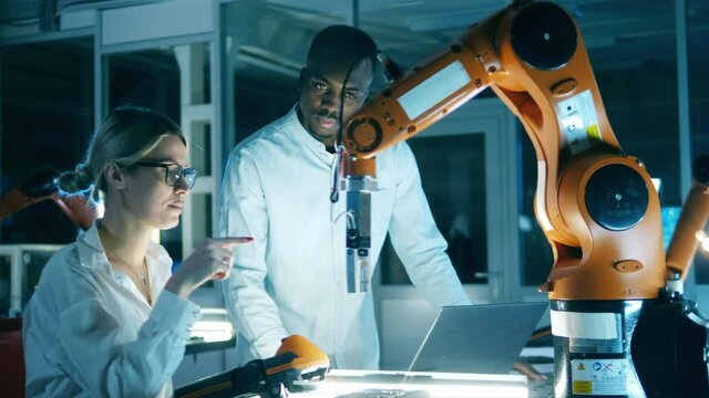 One engineer explaining to another industrial robotic arm complex motions. Innovation, technology concept.