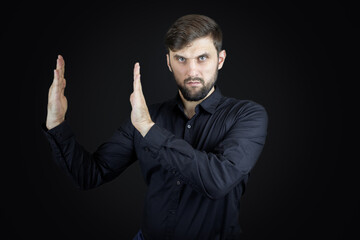a man in a black shirt and on a black background shows the palms of his hands gestures