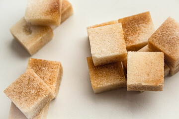 Reed sugar in the form of cubes lies on a white background with a handful