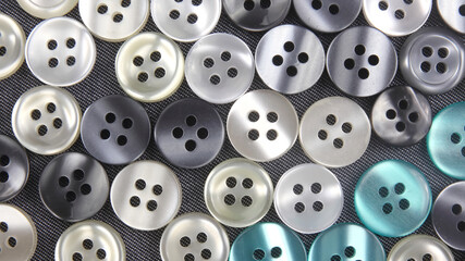 Plastic shiny buttons for clothes on a fabric background. Fashion and clothing. Factory industry