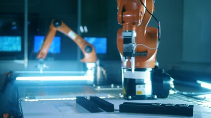 Orange robotic arm picks microchip and moves it to another place