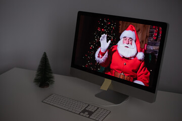 Santa Claus remotely wishes Merry Christmas via a video call on the computer. A man dressed as Santa Claus on a monitor. 2021 new year concept