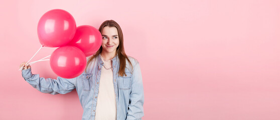 Fototapeta na wymiar Young caucasian woman holding balloons with happy expression and celebrating a Valentine's day isolated over a pink background