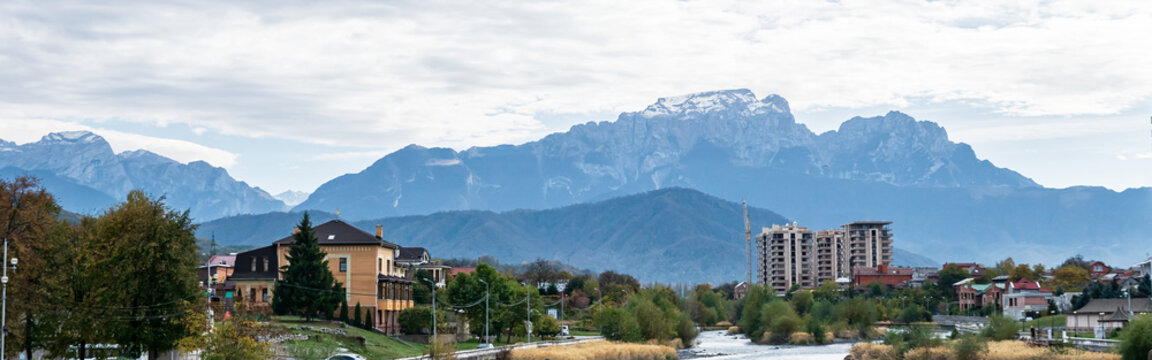 Panorama of the city against the background of a snow-capped mountain, river valley. - Powered by Adobe
