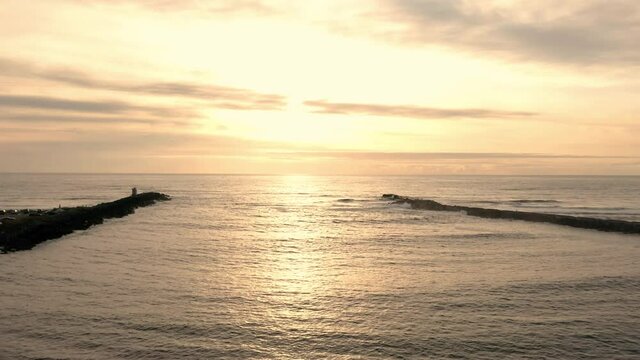Drone flying between North and South jetty in Bandon Oregon at sunset