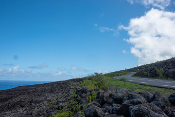 Volcanic and sea landscape with a road on the flanks of the Piton de la Fournaise in Réunion island, tropical active volcano, France.
