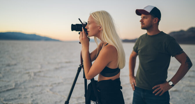 Young couple using photo camera for taking picture of terrain