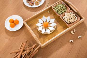 Pile of orange Indian  and continental sweets with spices on wooden table.