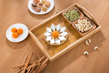 Pile of orange Indian  and continental sweets with spices on wooden table.