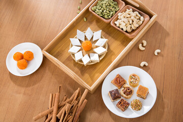 Pile of orange Indian  and continental sweets with spices on wooden table.