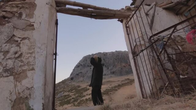 Hombre con chaquet&oacute;n negro contemplando el amanecer desde un cortijo abandonado en la monta&ntilde;a