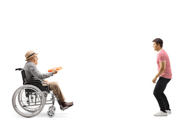 Full length profile shot of an elderly man in a wheelchair playing throwing a plastic disk with a...