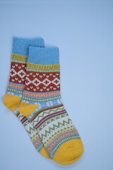 socks with a pattern on a light blue background.Winter warm knitted socks with a multicolored variegated pattern
