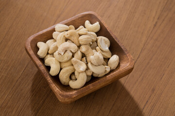 Wooden bowls of cashews on wooden table.